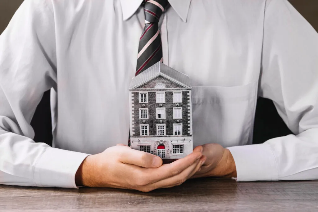 man-holding-miniature-house-hands